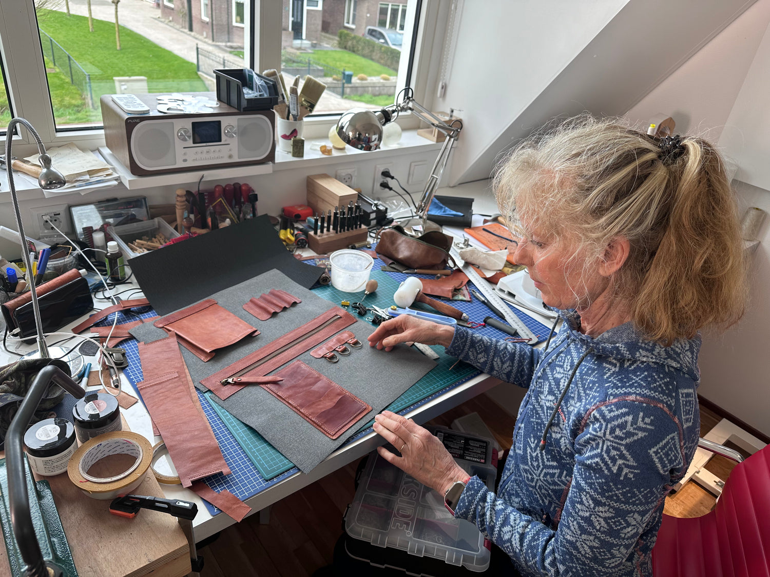 Op deze foto zie je Dineke Prins van Bolsas Tassen aan het werk met een tas die ze maakt. Je ziet materiaal, leer en meer in haar atelier